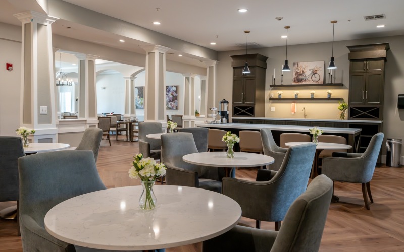 resident kitchen and dining area with chairs and table and a bar with bar stools